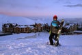 Pretty Girl snowboarder stands on front of hotel ski resort