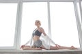 Girl practicing yoga, doing splits, stretching exercise on windowsill at home Royalty Free Stock Photo