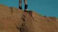 A pretty girl is standing on the edge of a sand dune with a snowboard or sandboard. Sexy lady tramples on the edge of a