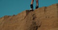 A pretty girl is standing on the edge of a sand dune with a snowboard or sandboard. Sexy lady tramples on the edge of a