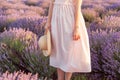 Pretty girl standing in the lavender field with fedora hat in her hand Long pink dress