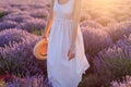 Pretty woman standing in the lavender field holding fedora hat in her hand