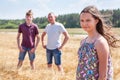 Pretty girl in summer light dress portrait with her father and brother on background, Caucasian family in wheat field