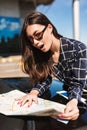 Pretty girl in sunglasses leaning on black car while amazedly looking road on map with airport on background Royalty Free Stock Photo