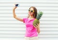 Pretty girl in sunglasses with pineapple taking picture selfie on smartphone Royalty Free Stock Photo