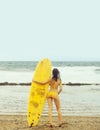 Pretty girl surfer in swimsuit holding yellow surfboard Royalty Free Stock Photo