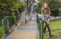 Pretty girl in a sweater sitting on a railing street stairs. Royalty Free Stock Photo