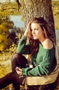 Pretty girl in sweater sunning under tree on Royalty Free Stock Photo