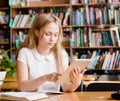 Pretty girl with tablet computer working in library Royalty Free Stock Photo