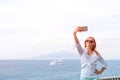 Pretty girl Takes a selfie photo. Sea and horizon in the background. Vacation and travel concept. Communication on a mobile Royalty Free Stock Photo