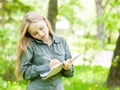 Pretty girl talking on the phone and writes in notebook Royalty Free Stock Photo