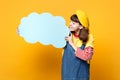Pretty girl teenager in french beret, denim sundress looking on blue empty blank Say cloud, speech bubble in hands Royalty Free Stock Photo
