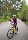 Pretty girl teenager in a helmet rides a bicycle and reads a book with enthusiasm in motion