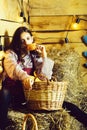 Pretty girl on straw bales with wicker basket on rustic background