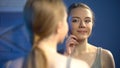 Pretty girl touching facial skin near mirror, satisfied with reflection, beauty Royalty Free Stock Photo