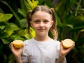 Pretty girl with two halves of fresh lemon. Caucasian girl holding lemon and smiling. Selected focus. Green tropical leaves