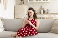 Pretty girl using smartphone seated on sofa in cozy apartment Royalty Free Stock Photo