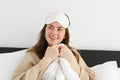 Pretty girl wakes up in morning, lying on pillow covered with white duvet, smiling at camera, wakes-up and looks happy Royalty Free Stock Photo