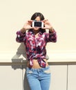 Pretty girl wearing a checkered shirt makes photo self-portrait on the smartphone outdoors