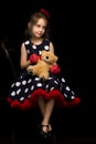 Pretty Girl in Polka Dot Dress Sitting on Isolated Black Background. Royalty Free Stock Photo