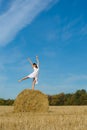 Pretty girl in white dress on haystack in field