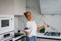 Pretty girl in a white T-shirt is standing in the kitchen and holding a white vase with red, ripe cherries. The concept of healthy Royalty Free Stock Photo