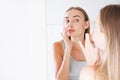 Pretty girl, woman touching her nose while looking in the mirror, beauty concept,plastics Royalty Free Stock Photo