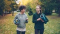 Pretty girls are walking in park holding yoga mats and talking discussing sports equipment, smiling and laughing Royalty Free Stock Photo