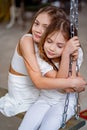 pretty girls in white clothes rides on swing. children& x27;s friendship.