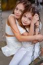 pretty girls in white clothes rides on swing. children& x27;s friendship.