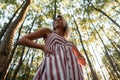 Pretty glamorous young woman with blond hair in a fashionable striped pink dress posing on the background of a trees Royalty Free Stock Photo