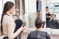 Pretty hair stylist showing man new haircut