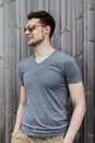 Pretty handsome young man hipster with sunglasses smiling laughing behind wooden wall. Looking aside.