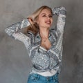 Pretty happy beautiful young blond woman with a cute smile in a vintage gray shirt with a pattern in a white t-shirt Royalty Free Stock Photo