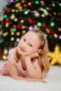 pretty and happy blonde little girl in pink dresses at the Christmas tree.