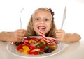 Pretty happy Caucasian female child eating dish full of candy in sweet sugar abuse dangerous diet