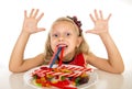 Pretty happy Caucasian female child eating dish full of candy in sweet sugar abuse dangerous diet