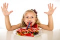 Pretty happy Caucasian female child eating dish full of candy in sweet sugar abuse dangerous diet