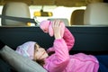Pretty happy child girl playing with a pink toy teddy bear in a car trunk Royalty Free Stock Photo