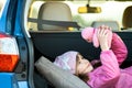 Pretty happy child girl playing with a pink toy teddy bear in a car trunk Royalty Free Stock Photo