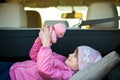 Pretty happy child girl playing with a pink toy teddy bear in a car trunk Royalty Free Stock Photo