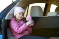 Pretty happy child girl playing with a pink toy teddy bear sitting in a car trunk Royalty Free Stock Photo