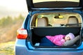 Pretty happy child girl sleeping with a pink toy teddy bear in a car trunk Royalty Free Stock Photo