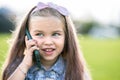 Pretty happy child girl talking on mobile phone smiling outdoors in summer Royalty Free Stock Photo