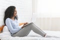 Pretty happy girl sitting on bed, using laptop Royalty Free Stock Photo