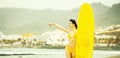 Pretty happy girl surfer with yellow surfboard points finger Royalty Free Stock Photo