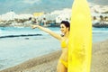 Pretty happy girl surfer with yellow surfboard points finger Royalty Free Stock Photo