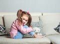 Pretty happy little girl in casual wearing sitting on sofa with toy dog and smiling. Royalty Free Stock Photo