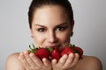 Pretty happy smiling girl with many strawberry over colorful white background.Portrait of brunette cutie with bowl of