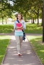 Pretty happy student carrying notebook walking Royalty Free Stock Photo